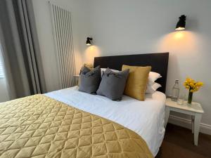 福克斯通Bouverie Bolthole的一间卧室配有一张大床,提供黄色和灰色的枕头