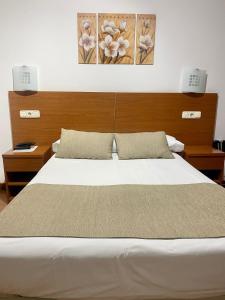 圣地亚哥－德孔波斯特拉Pensión Residencia Fornos的卧室配有一张带两个灯的大白色床