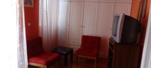 MantoúkionDora's happy apartment的客厅配有2把红色椅子和电视