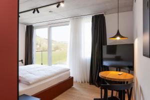 屈斯纳赫特Tailormade Hotel RIGIBLICK Küssnacht的一间卧室配有一张床、一张桌子和一个窗户。