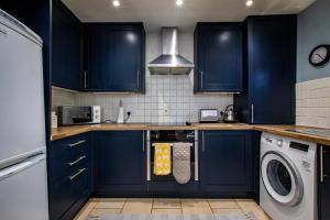 伊尔克利Carr Croft Lodge - Ilkley Centre的厨房配有蓝色橱柜、洗衣机和烘干机