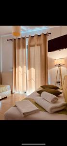 米尔托斯Myrthe Apartments的卧室配有白色窗帘和1张带2条毛巾的床