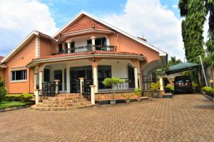 坎帕拉Beautiful home opposite Speke Resort Munyonyo near Lake Victoria的砖车道上带阳台的房子