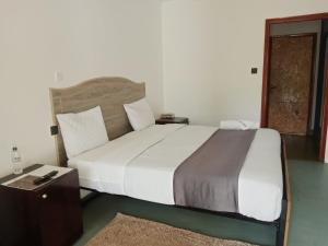 纳纽基Riverside Villas Nanyuki的卧室配有一张白色的大床和一张桌子