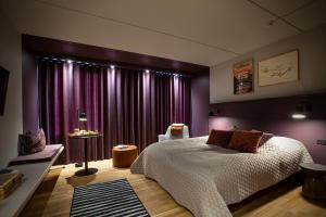 埃斯比约不列颠尼亚酒店的一间卧室配有一张床和一个带紫色窗帘的窗户