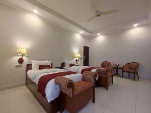 伊斯兰堡Welcome Hotel Islamabad的酒店客房,配有两张床和两把椅子
