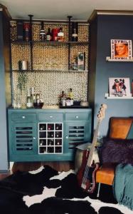 森伯里The Tranquil Traveller的一间房间,里面装有蓝色的橱柜和吉他