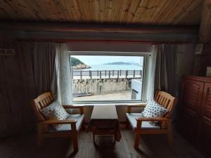 南竿马祖牛角海边民宿餐饮的客房设有两把椅子、一张桌子和大窗户