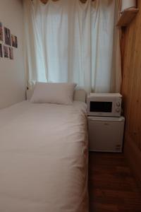 首尔Hostel JL in Chung-jeong的一间小卧室,配有一张床和一台微波炉