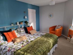 南塞尔尼Windrush Turret Lodge的一间卧室配有一张床和一张橙色椅子
