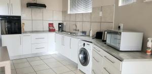 温特和克Feather Self Catering Accommodation的厨房配有白色橱柜和洗衣机。