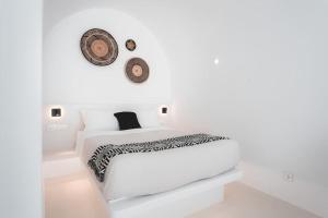 安坡里奥圣托里尼AKRI santorini with heated jacuzzi的白色的卧室配有一张床和墙上的时钟