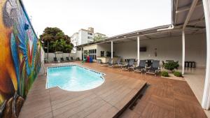 戈亚尼亚Allegro Hotel的一座带甲板和椅子的建筑中的游泳池