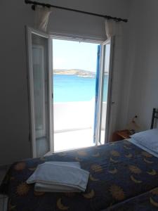 考弗尼西亚Glaros Rooms的一间卧室设有一张床,并拥有一扇通向大海的开放式门