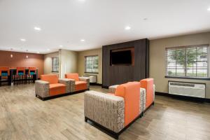 雷内克萨郊区长住酒店的一间配备有橙色椅子和平面电视的等候室