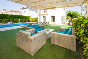 普罗塔拉斯Villa Emily的一个带藤椅和桌子的庭院和一个游泳池