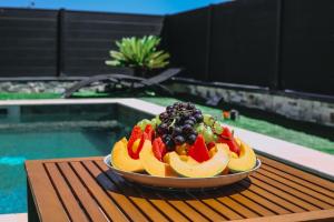 瑞维尼亚克Grande Villa cosy avec piscine, sauna & jacuzzi的游泳池畔的桌子上放上一碗水果