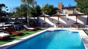 维拉卡洛斯帕兹米拉多尔代拉斯山脉酒店的一个带遮阳伞和椅子的游泳池以及一个游泳池