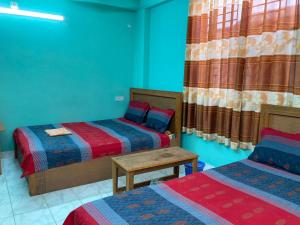 达卡Hotel Shahin Residential Jatrabari的客房设有两张床、一张桌子和窗帘