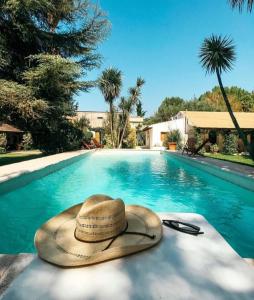 查克拉斯德科里亚Casa de Coria的坐在游泳池旁的草帽