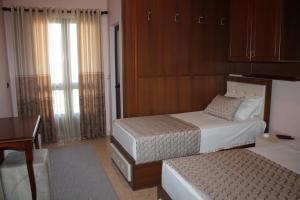 Mjedë哈斯米加酒店的一间卧室配有两张床、一张桌子和一张书桌