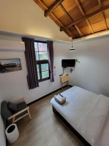 龙潭OLD WOW老屋瓦共享民宿Hostel 桃園市民宿074號的一间卧室配有一张床、一把椅子和电视。