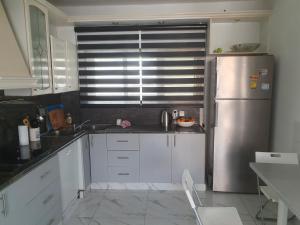 内坦亚CHAMBRE BLEUE 2 PERSONNES的厨房配有白色橱柜和不锈钢冰箱