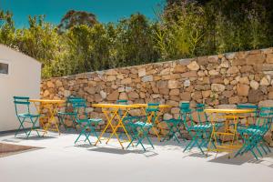 切法卢Villa Totò Resort的一组桌子和椅子,在石墙前