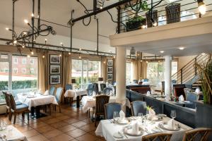 瓦尔内明德戈德温酒店的餐厅设有白色的桌椅和窗户。