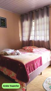 莫雷蒂斯Hospedaria Recanto dos Pássaros的一间卧室配有一张带粉色床单的床和一扇窗户。