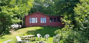 海沃德Tranquility On Teal Lake的一间红色的房子,前面设有野餐桌和椅子