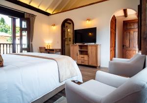 莱瓦镇Hotel Casa Alcestre的一间卧室配有一张床、两把椅子和电视