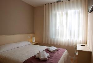 阿尔苏阿LA PUERTA DE ARZÚA的一间卧室配有床,窗户配有毛巾