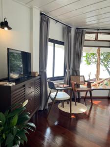 苏梅岛Boon Heritage House Koh Samui的客厅配有电视、椅子和窗户。
