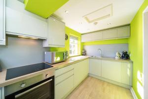 布莱尔高里Blindwelleyes Cottage的厨房配有白色橱柜和绿色墙壁