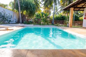 帕拉茹鲁Refugios Parajuru - Casa Pequena的一座拥有蓝色海水和棕榈树的游泳池
