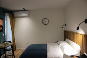地拉那Studio in Tirana的卧室配有一张床,墙上挂着一个钟