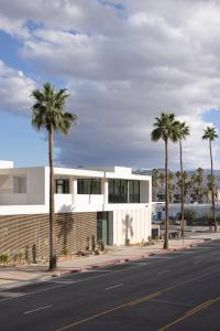 棕榈泉Drift Palm Springs的街道前方有棕榈树的建筑