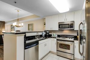 沃尔顿堡滩Waterscape A324的厨房配有白色橱柜和不锈钢用具