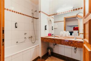 萨尔巴赫Dorfhotel Glücksschmiede的浴室设有2个水槽、浴缸和镜子