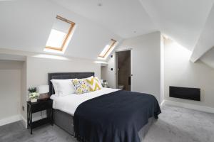 CockfostersSkyvillion - COZY LARGE 4 Bed Apartments in London Enfield, Mins to Tube Station, Free Wi-Fi的一间卧室设有一张床、一台电视和天窗。