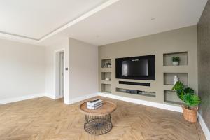 CockfostersSkyvillion - COZY LARGE 4 Bed Apartments in London Enfield, Mins to Tube Station, Free Wi-Fi的客厅配有电视和茶几