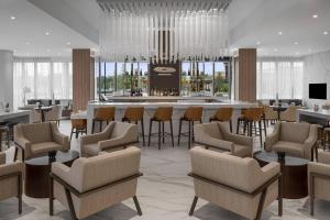 黎明城AC Hotel by Marriott Fort Lauderdale Sawgrass Mills Sunrise的大堂设有带椅子和桌子的酒吧