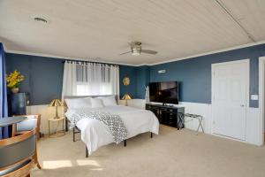 门罗Spacious Lakefront House with Backyard Fire Pit的一间卧室设有一张床、一台电视和蓝色的墙壁