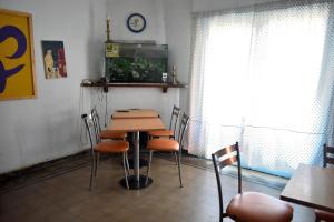 科尔多瓦Hostel Joven casa Reggae的墙上挂着时钟的房间里一张桌子和椅子