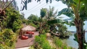 Gili GedeTanjungan的一个带椅子的木甲板和水边的小屋