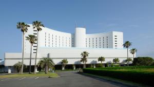 田原市伊良湖度假&会议酒店的一座白色的大建筑,前面有棕榈树