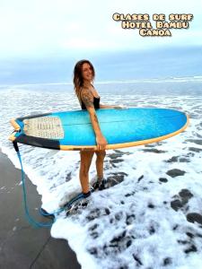 卡诺阿Hotel Bambú的站在海滩上,拿着冲浪板的女人