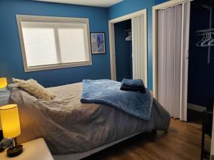 Oyster BaySaratoga beach cottage, private non-resort, easy beach access, 35mins Mt Washington的一间卧室配有一张蓝色墙壁的床和一扇窗户