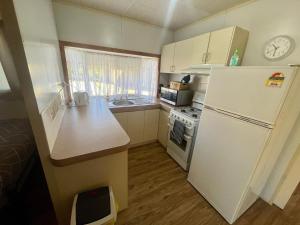 BroadwaterFamily Getaway Cabin 50的小厨房配有白色冰箱和炉灶。